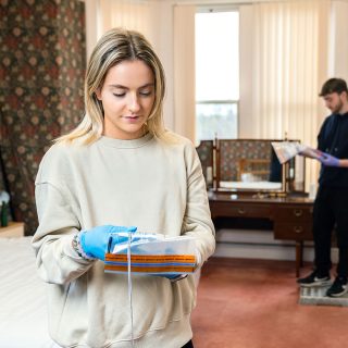 Image of Olivia Fowler holding an evidence bag in the Crime House.