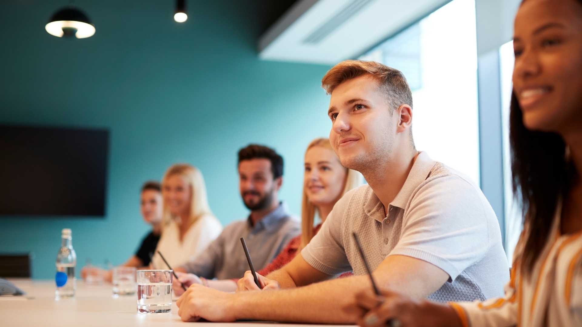 Man sat in boardroom looking off camera.