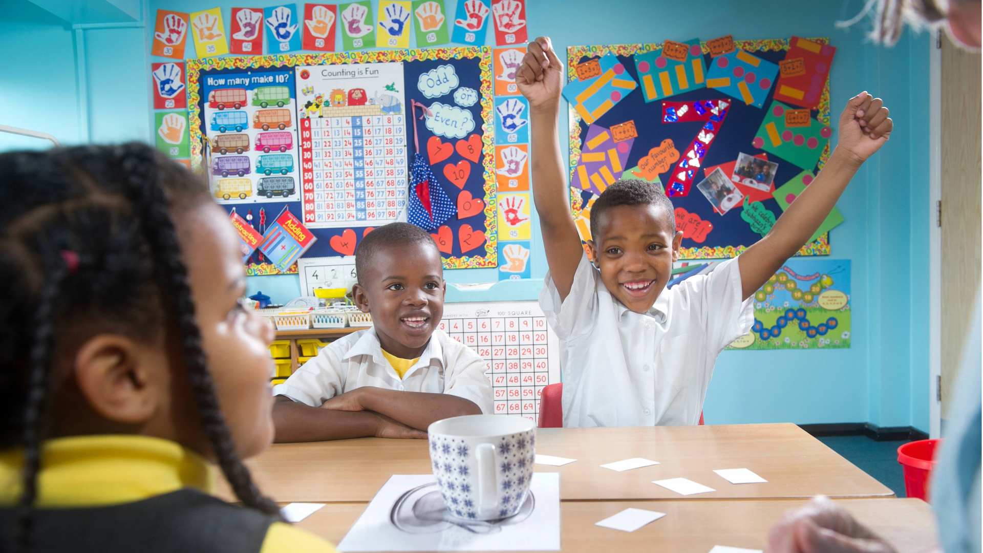 Group of primary age children cheering in the classroom at a table