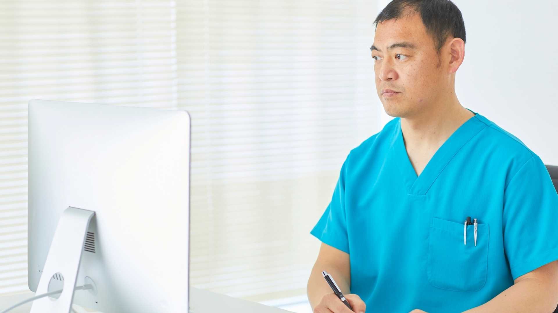 A doctor looks at a computer screen.