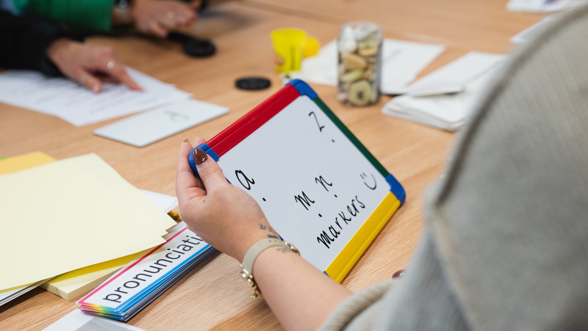 photo of teacher holding a mini white board with letters on it.