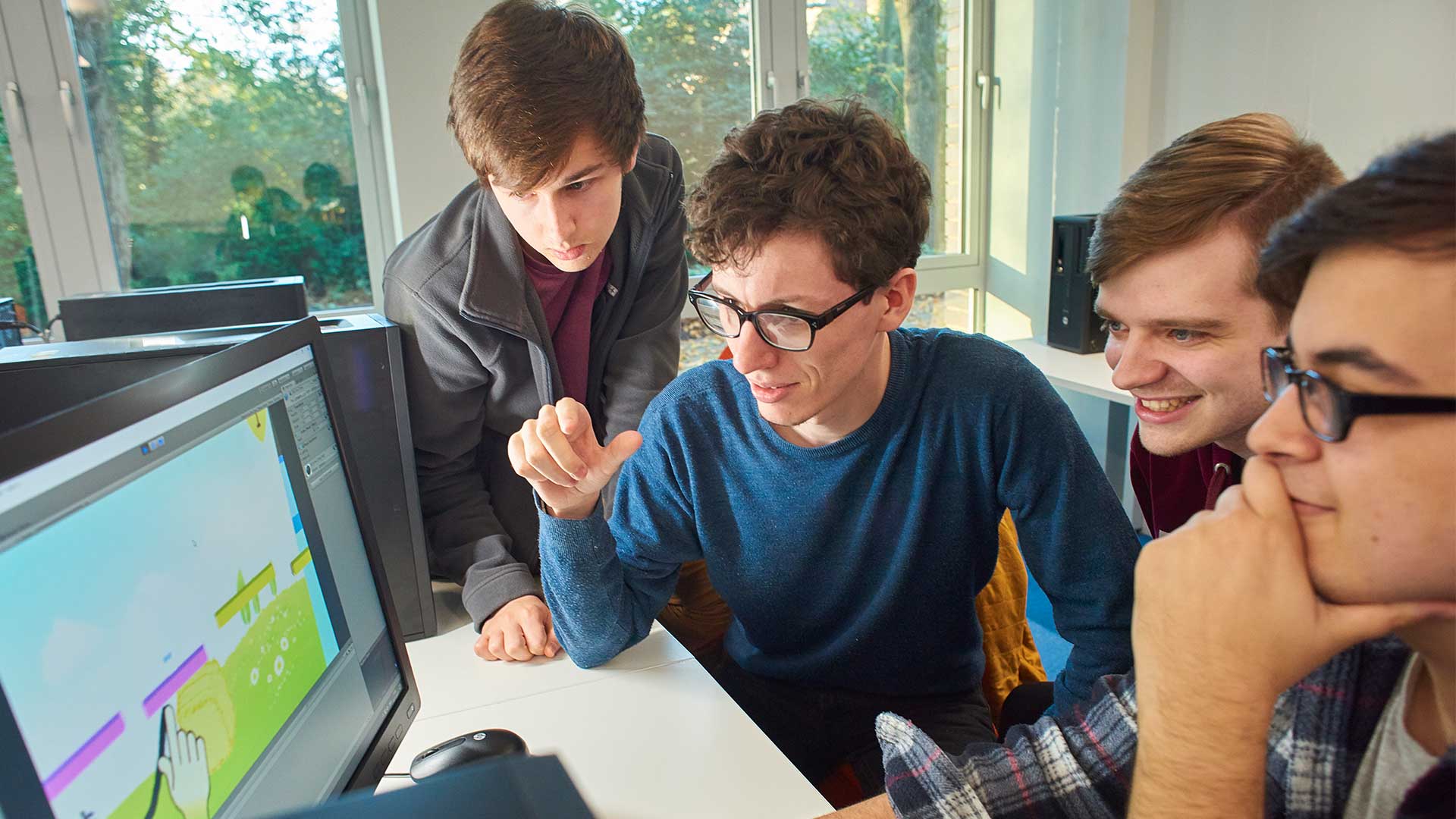 Students looking at a computer screen with a game design on it