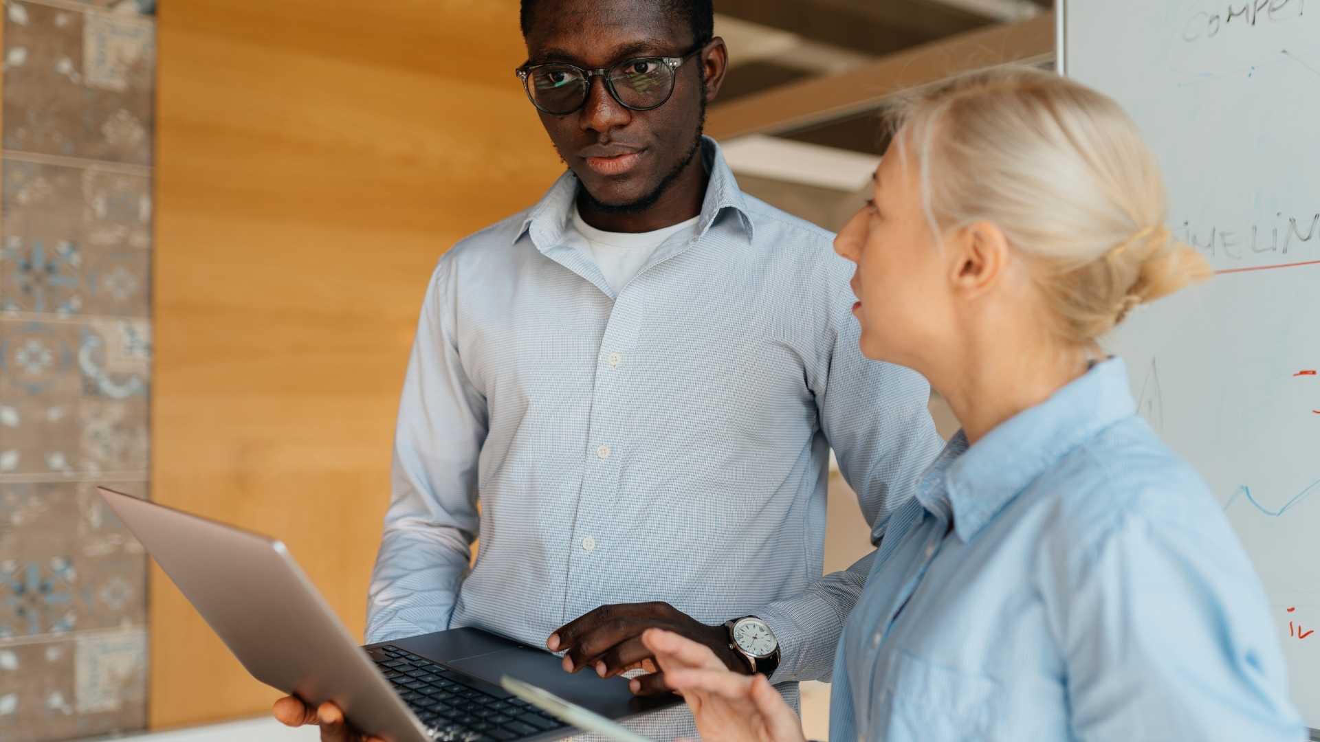 Man and woman in a business setting looking at a computer.