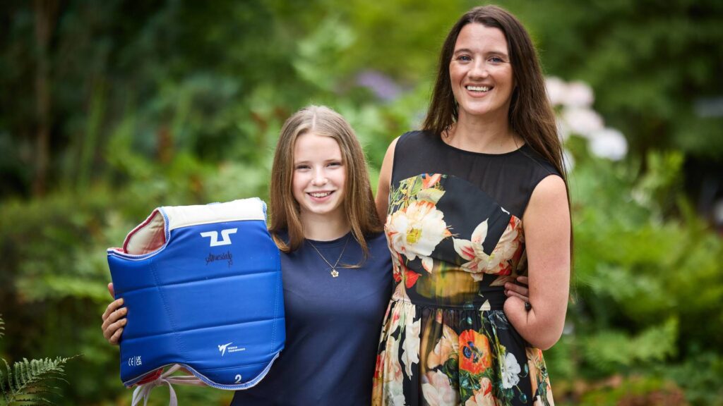 Amy Truesdale pictured smiling with Poppy Gleave holding her signed body armour.