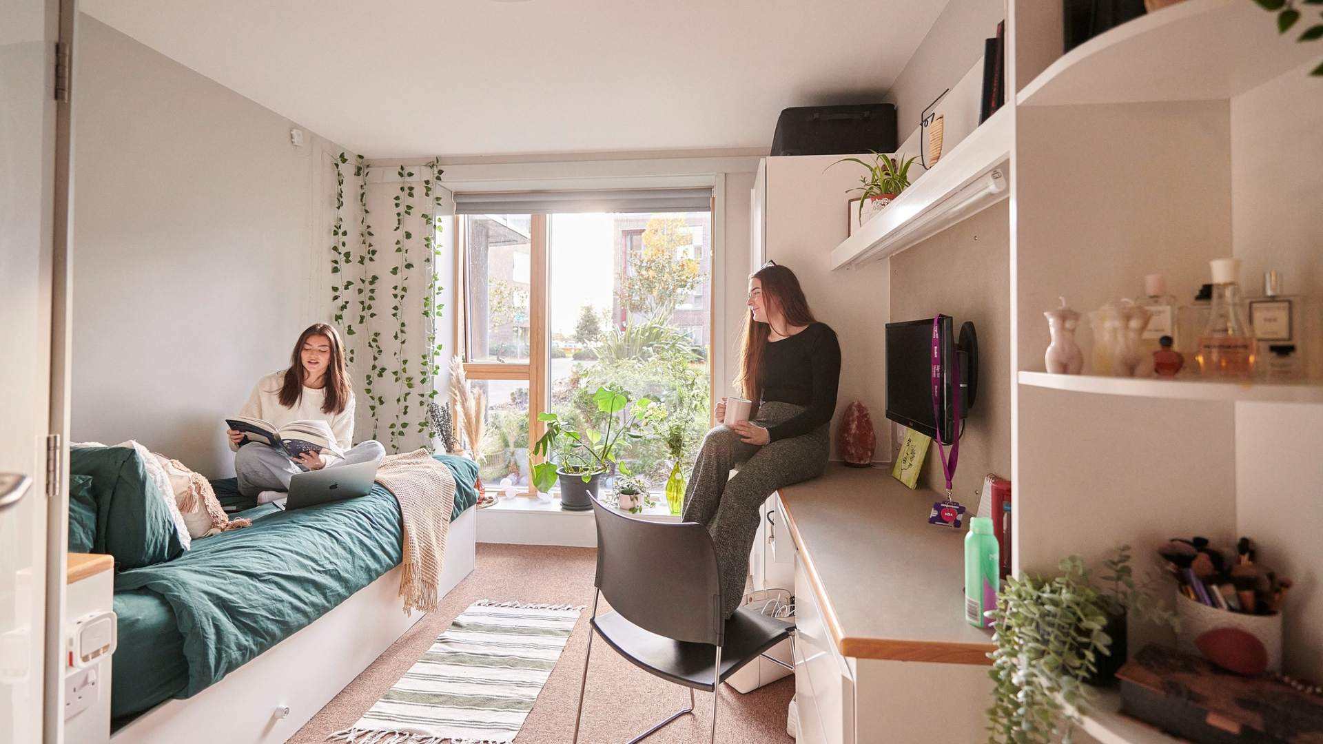 Students sit chatting in a campus accommodation room.