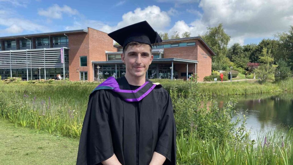 photo of Darol O'Kane outside EHU lake with his gown and cap