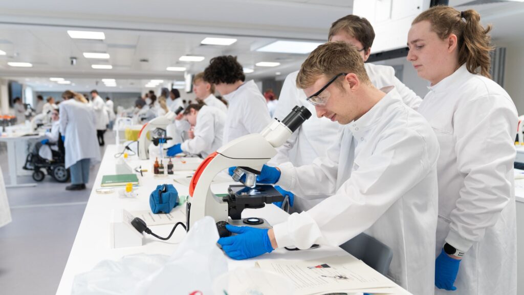 Students looking through microscope and using equipment in the Life Sciences building