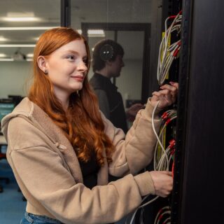 Evie Tarbuck ensuring all the wires are connected correctly to the server