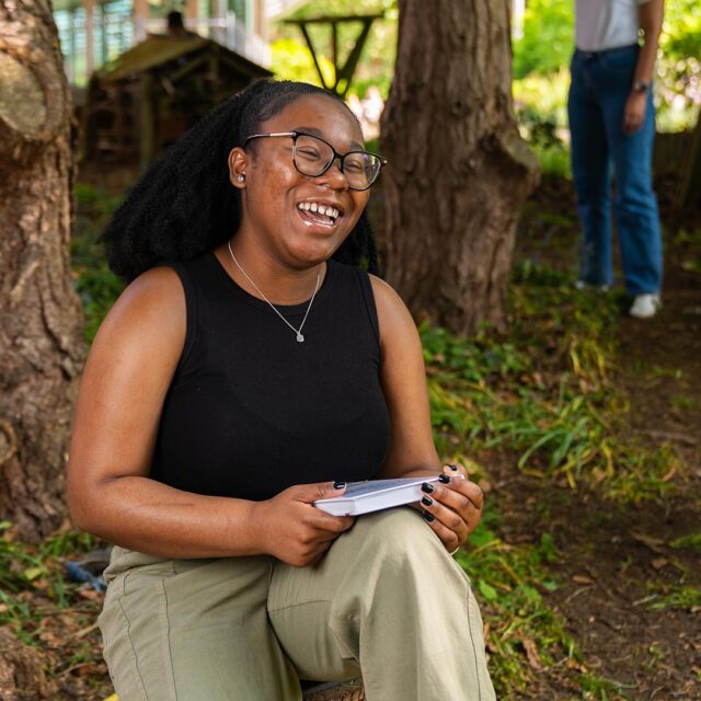 Kahlia Brackett profile photo, sat by a tree with a book