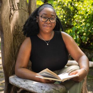 Kahlia Brackett profile photo, sat by a tree with a book
