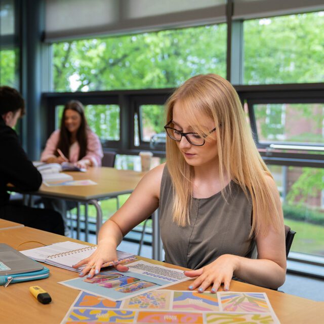 Katie sat at a desk analysing printed marketing material