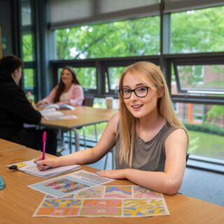Katie sat at a desk with pen and paper