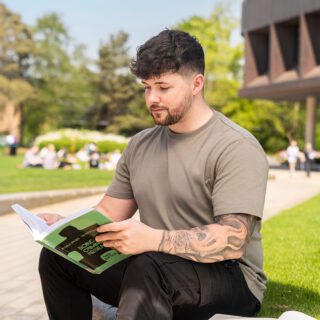 Niall reading a criminology book outside on Campus