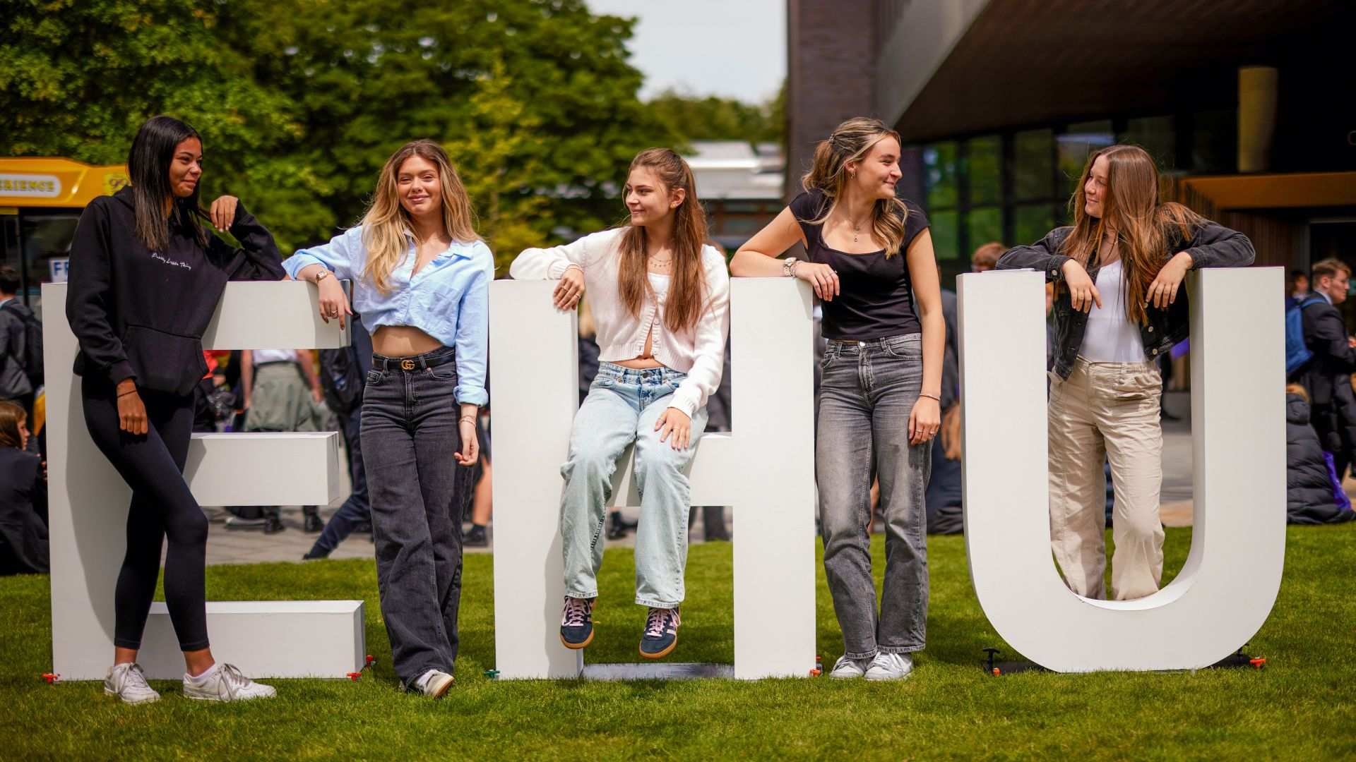 A group of students sit on or around giant letters EHU.
