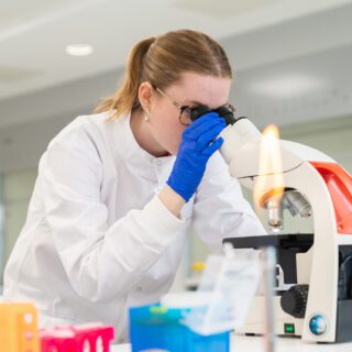 Alice Thomas looking through microscope