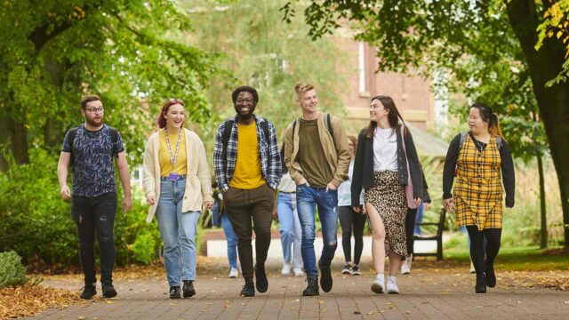 a group of happy students walking through our green campus
