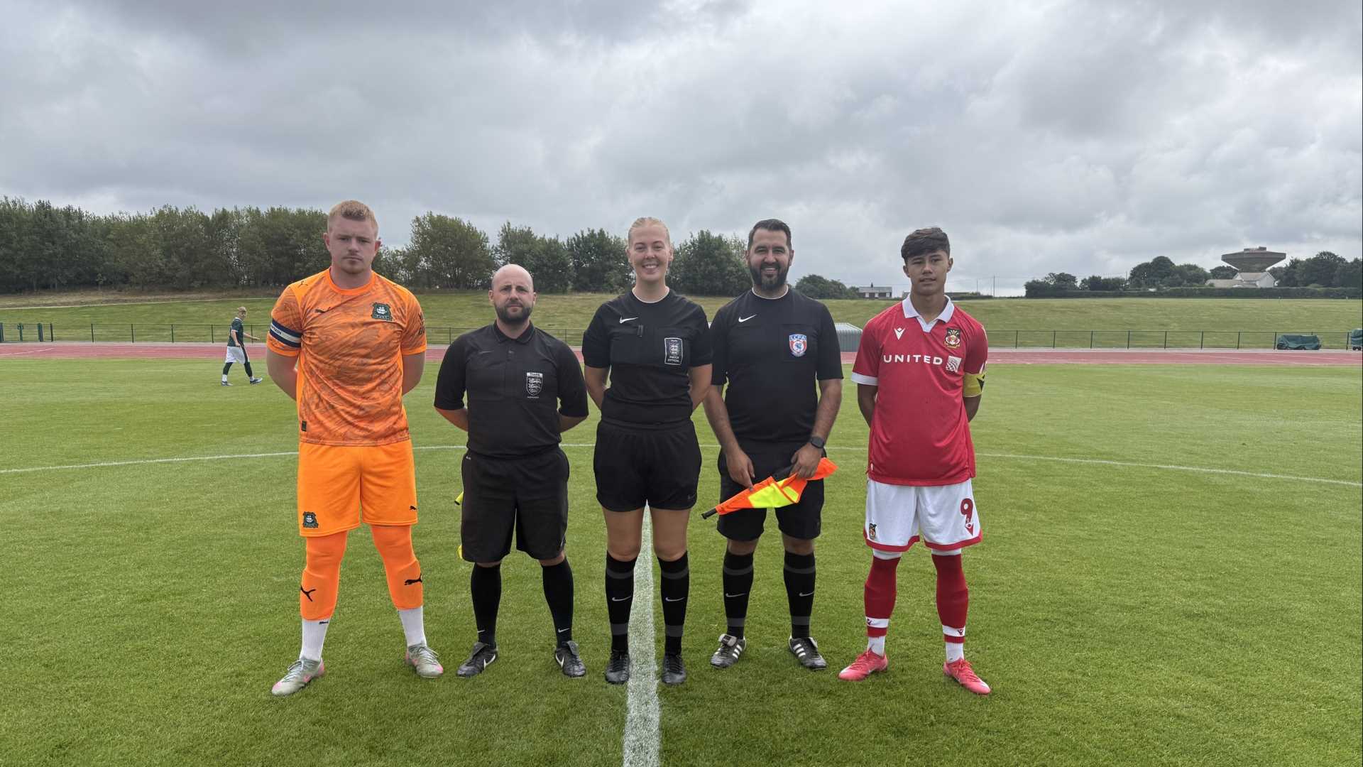 image of two referees and captains of football team on the football pitch