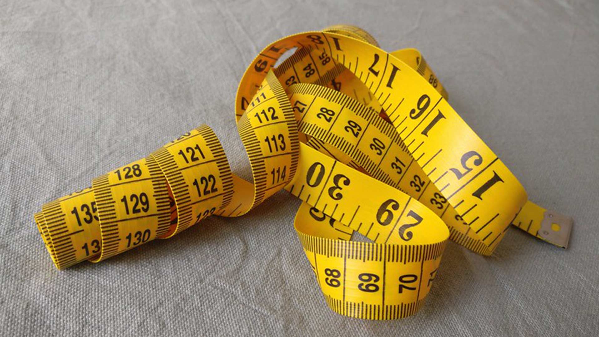 Yellow measuring tape on a grey background