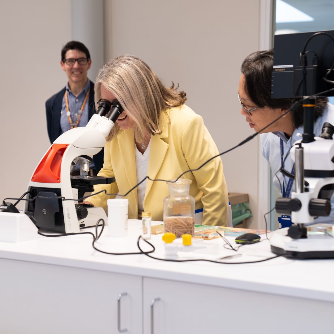 Skills Minister Jacqui Smith looks through a microscope in a science lab.