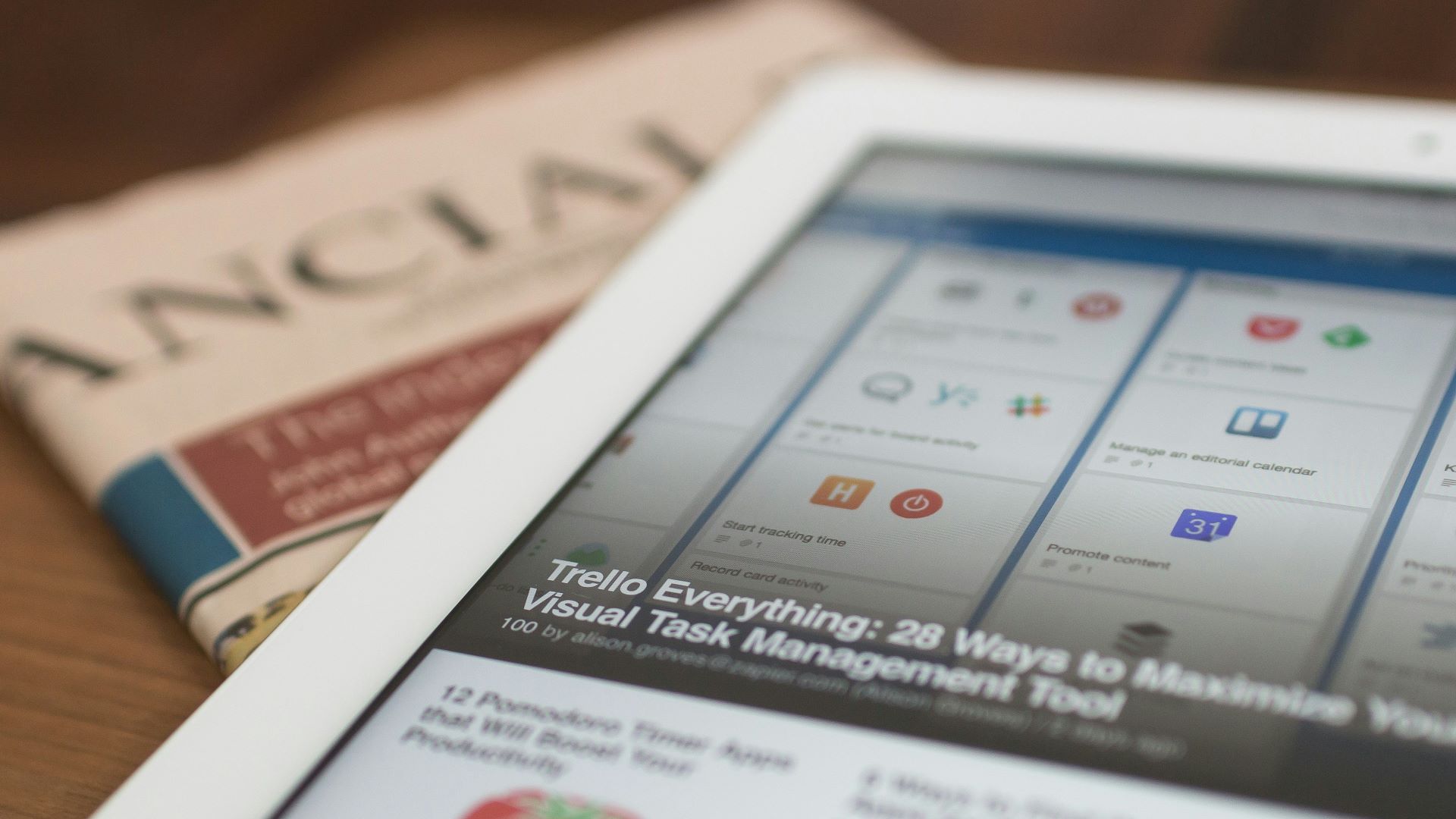 A tablet displaying news rests on top of a copy of the Financial Times.