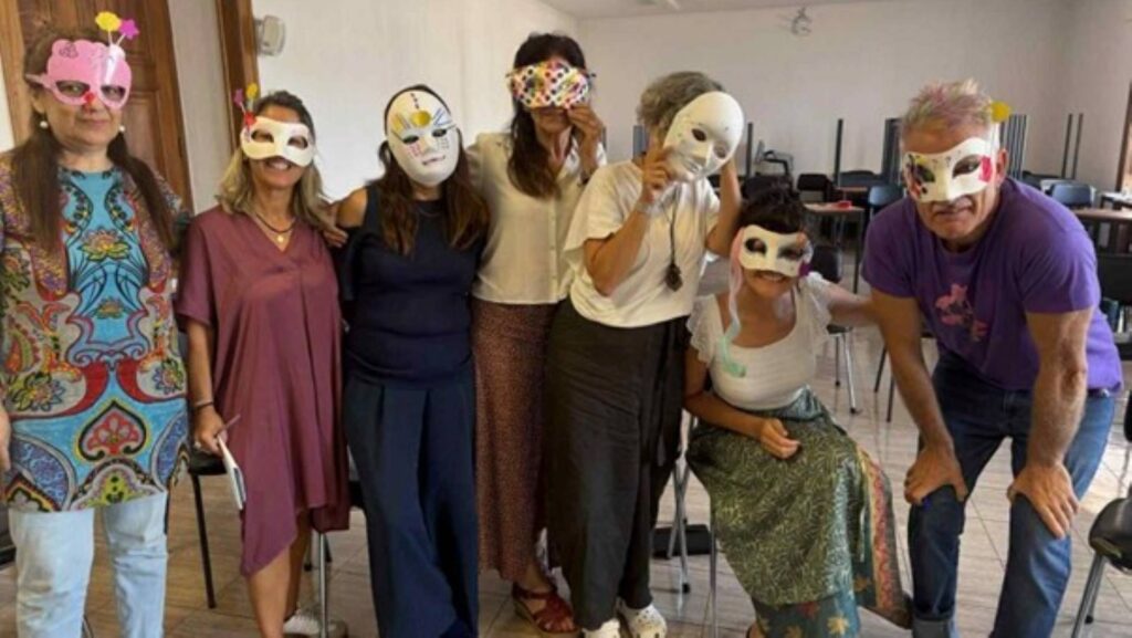 a group of seven people standing together with hand made masks on their faces. 