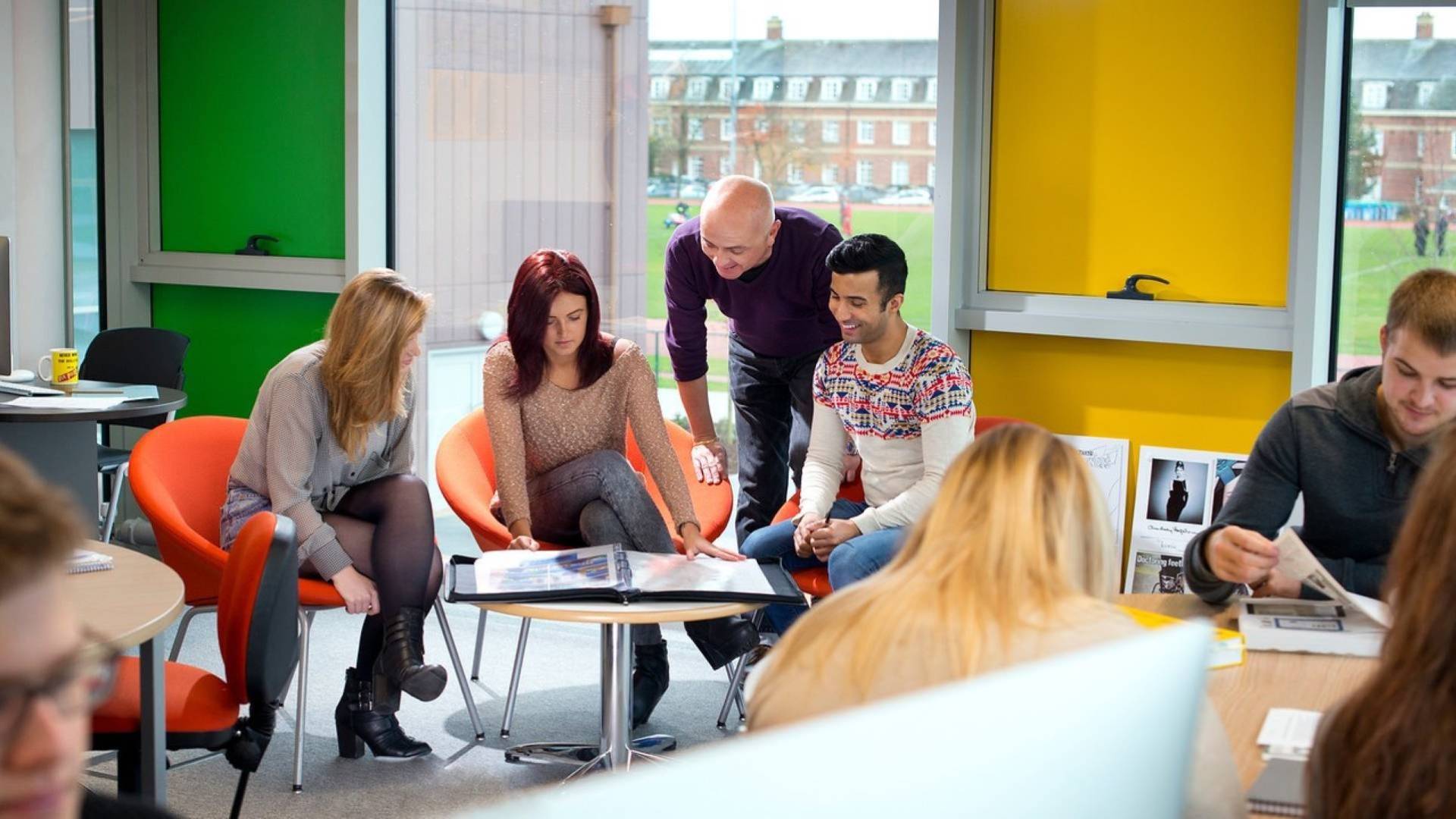 Group of students sat round a desk with green and yellow walls