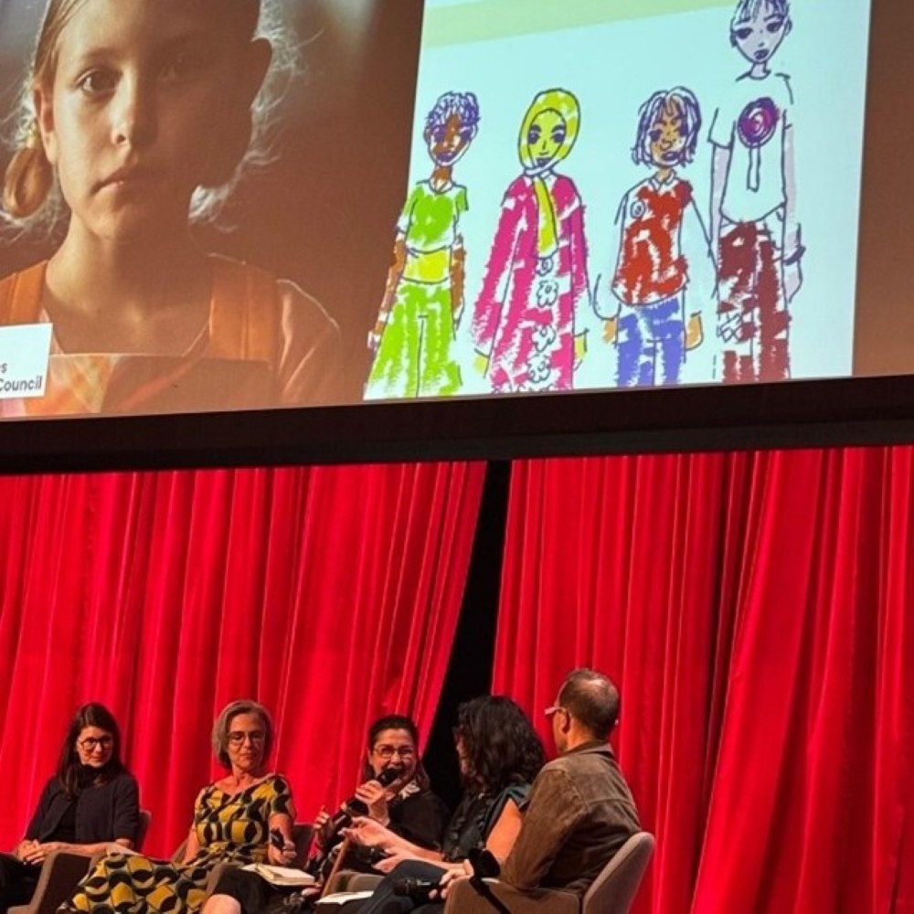 Professor Vicky Karkou on a panel with 4 other guests, she is currently holding the mic and speaking.