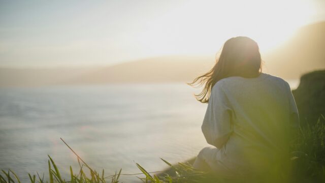 Photo of a woman on the beach looking out to the water.