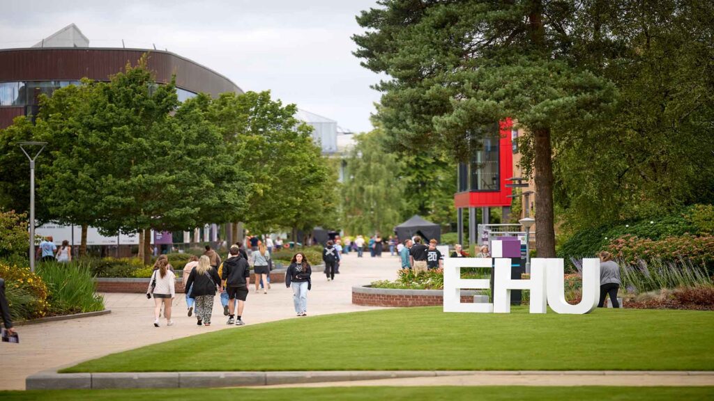 A shot of campus by the Hub with large "EHU" letters on the grass in front of the Wilson Building.