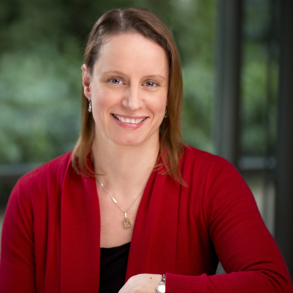 Portrait of staff member Katherine Knightly, looking straight at the camera, smiling and wearing red cardigan and black top. 