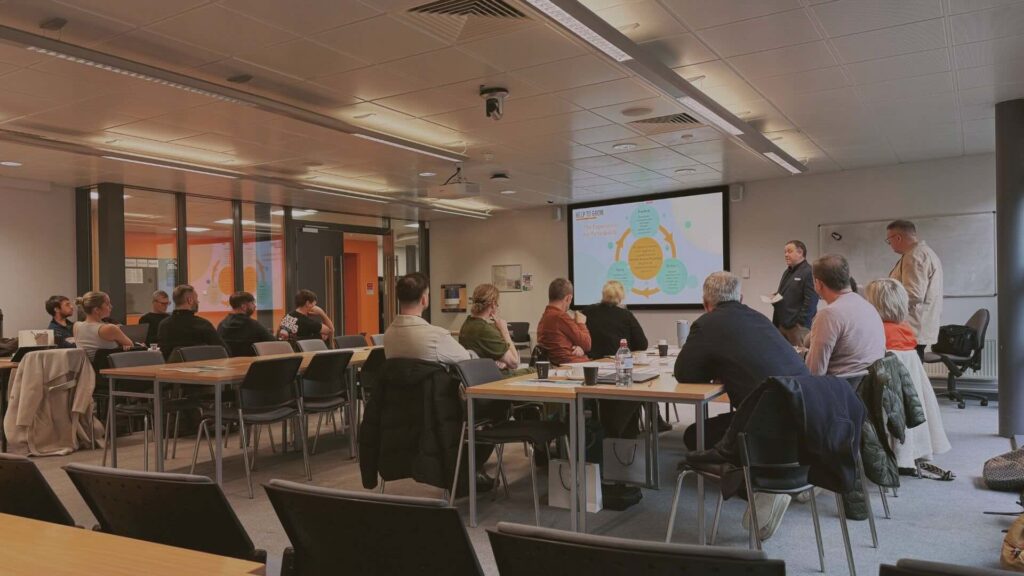class room filled with people and presentation on the big screen.