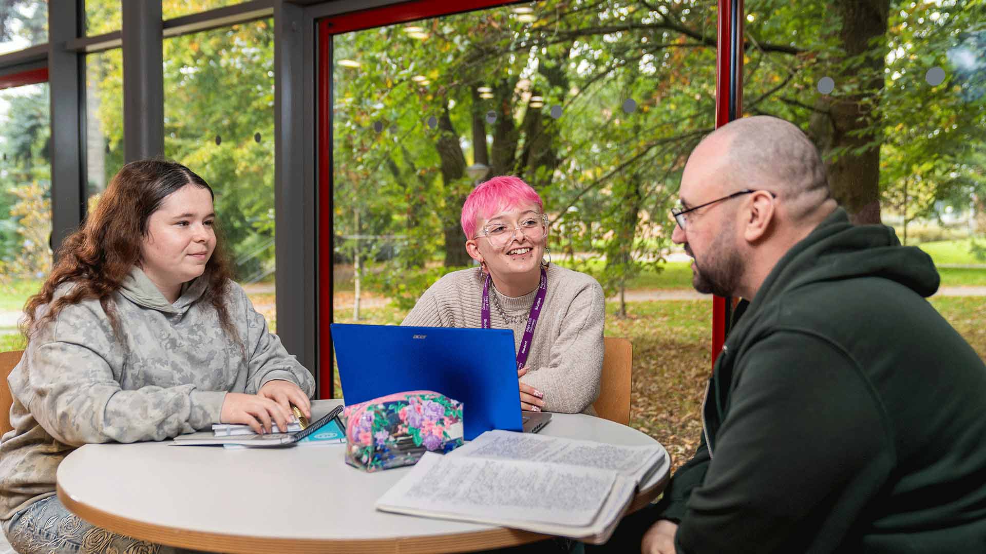 Students sat around a table talking with a laptop and notepad