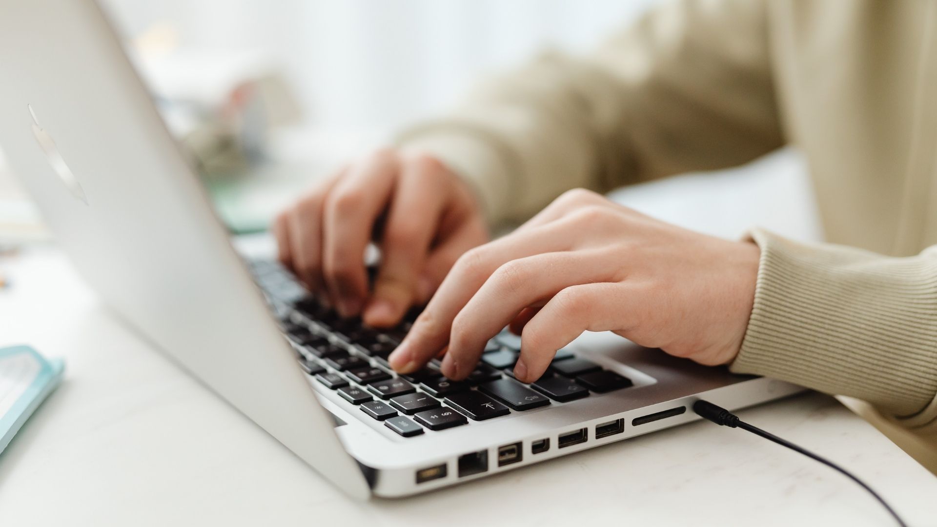 A man's hands type at a laptop keyboard.