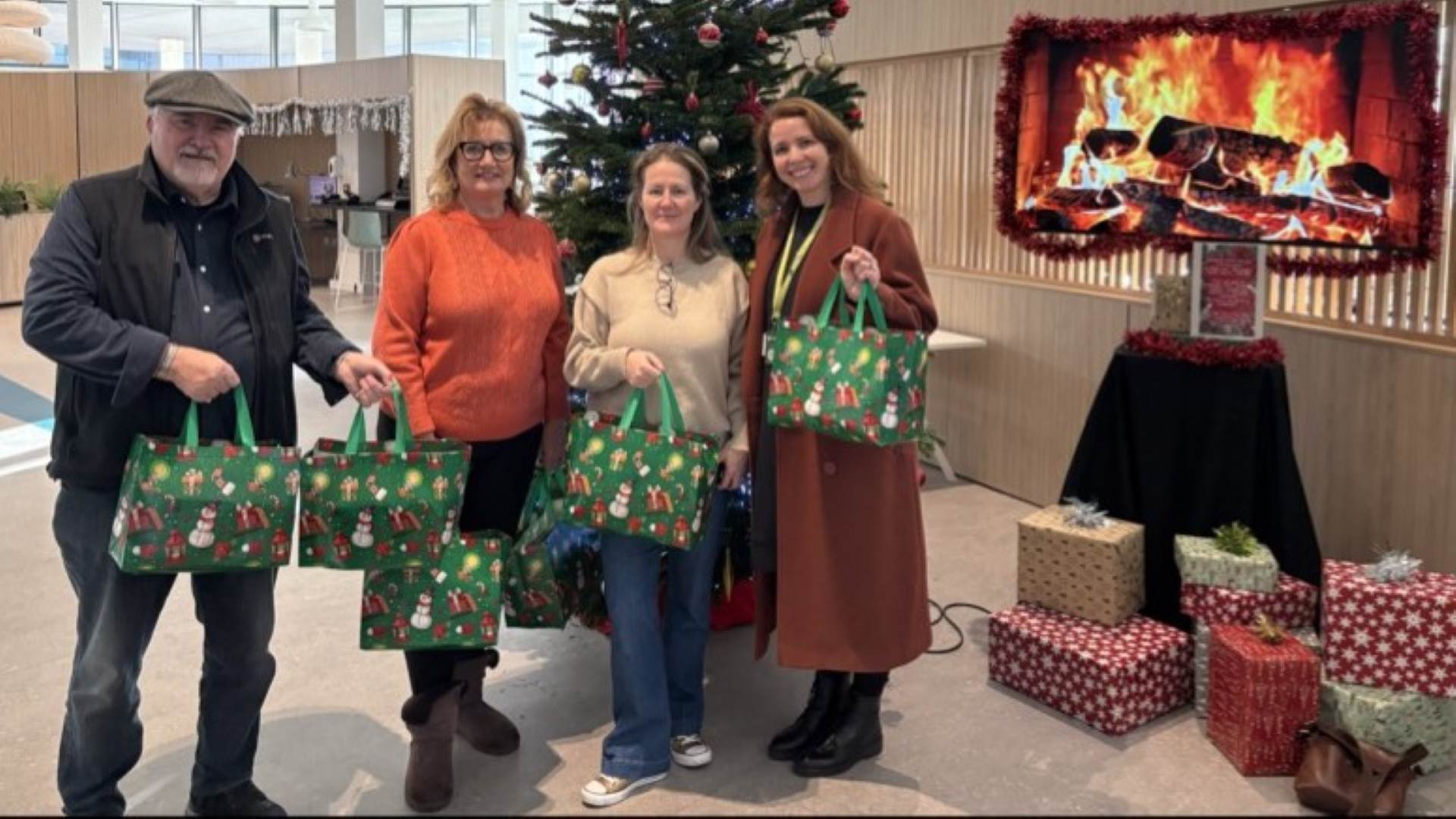 four people stranding behind a Christmas trees holding hampers at catalyst library.