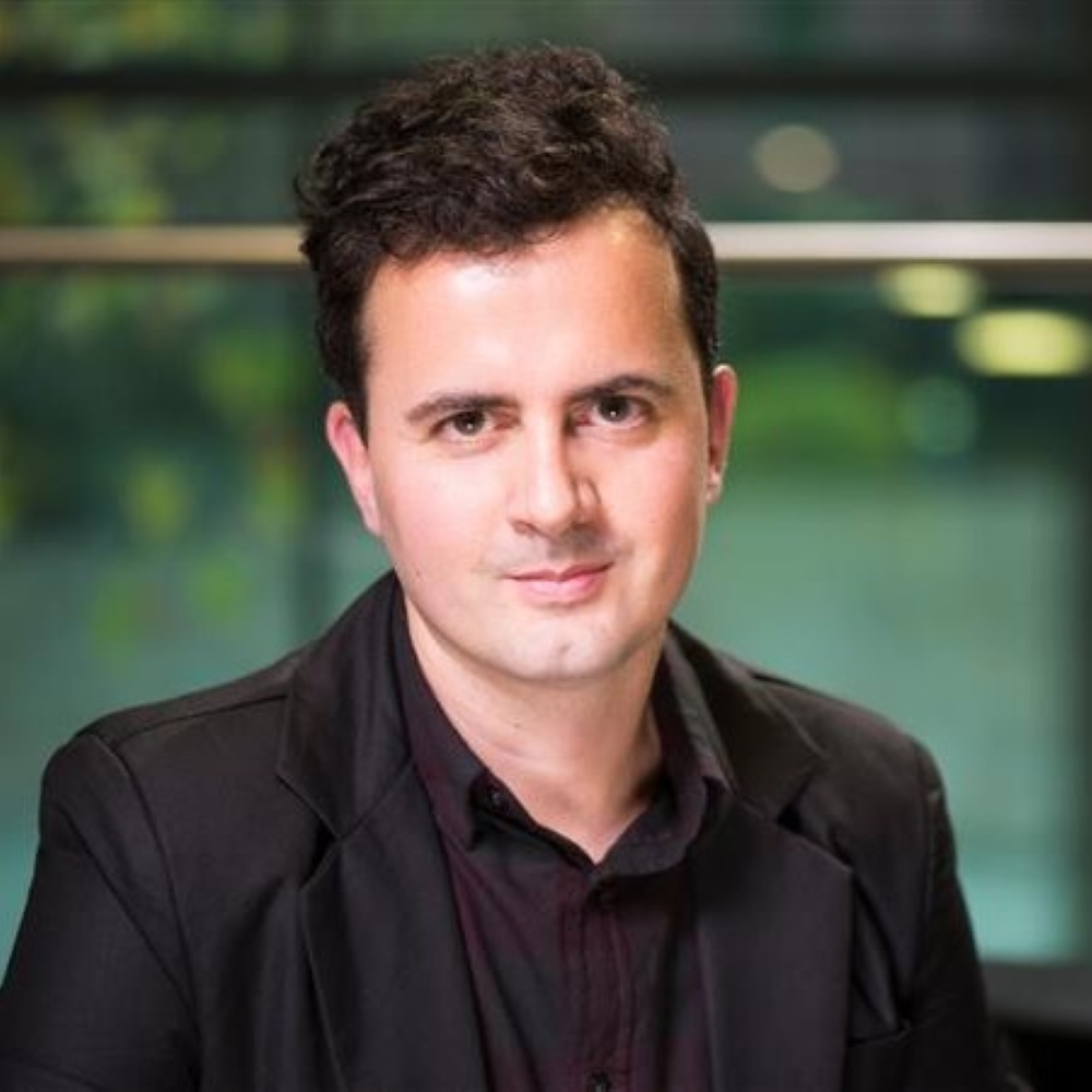 A doctor wearing scrubs and a lanyard presents to students