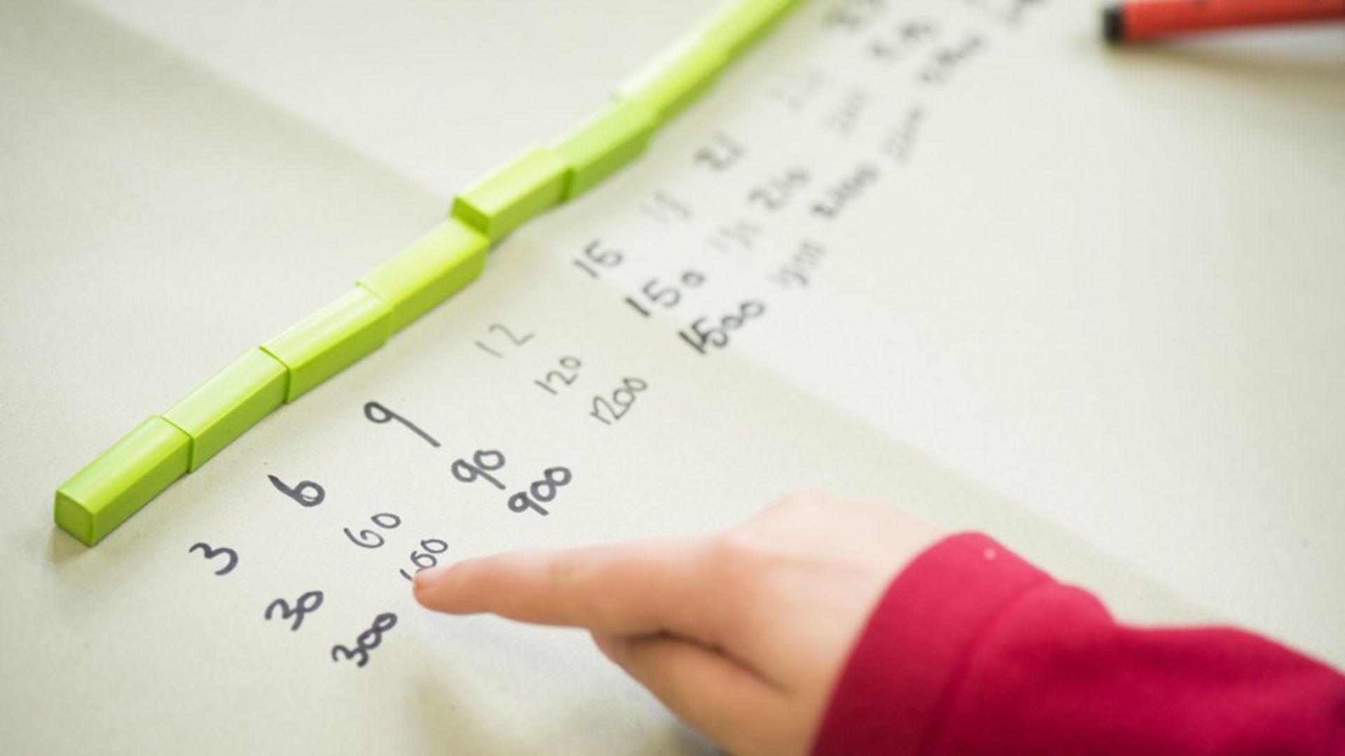 A child's hand is pointing at a number line, with blocks.
