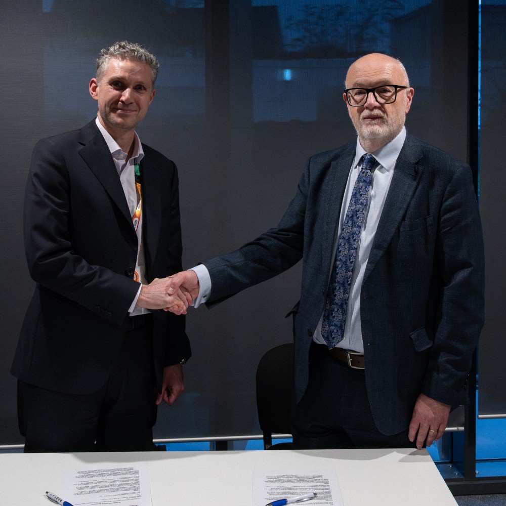 George Talbot from Edge Hill and Adam Bateman from Alder hey, both looking at the camera, shaking hands wearing blue suits and a tie