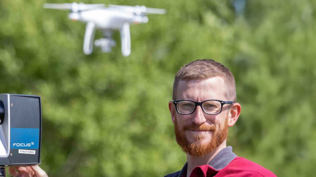 A person controlling a drone that flies above them.