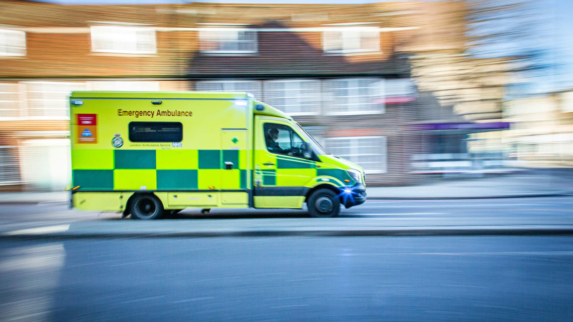 Ambulance travelling along a road. The ambulance is in focus but the background is blurred.