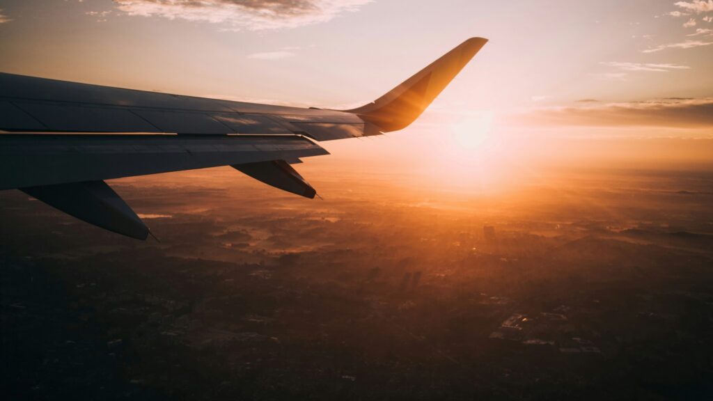 Image of plane wing flying at sunset