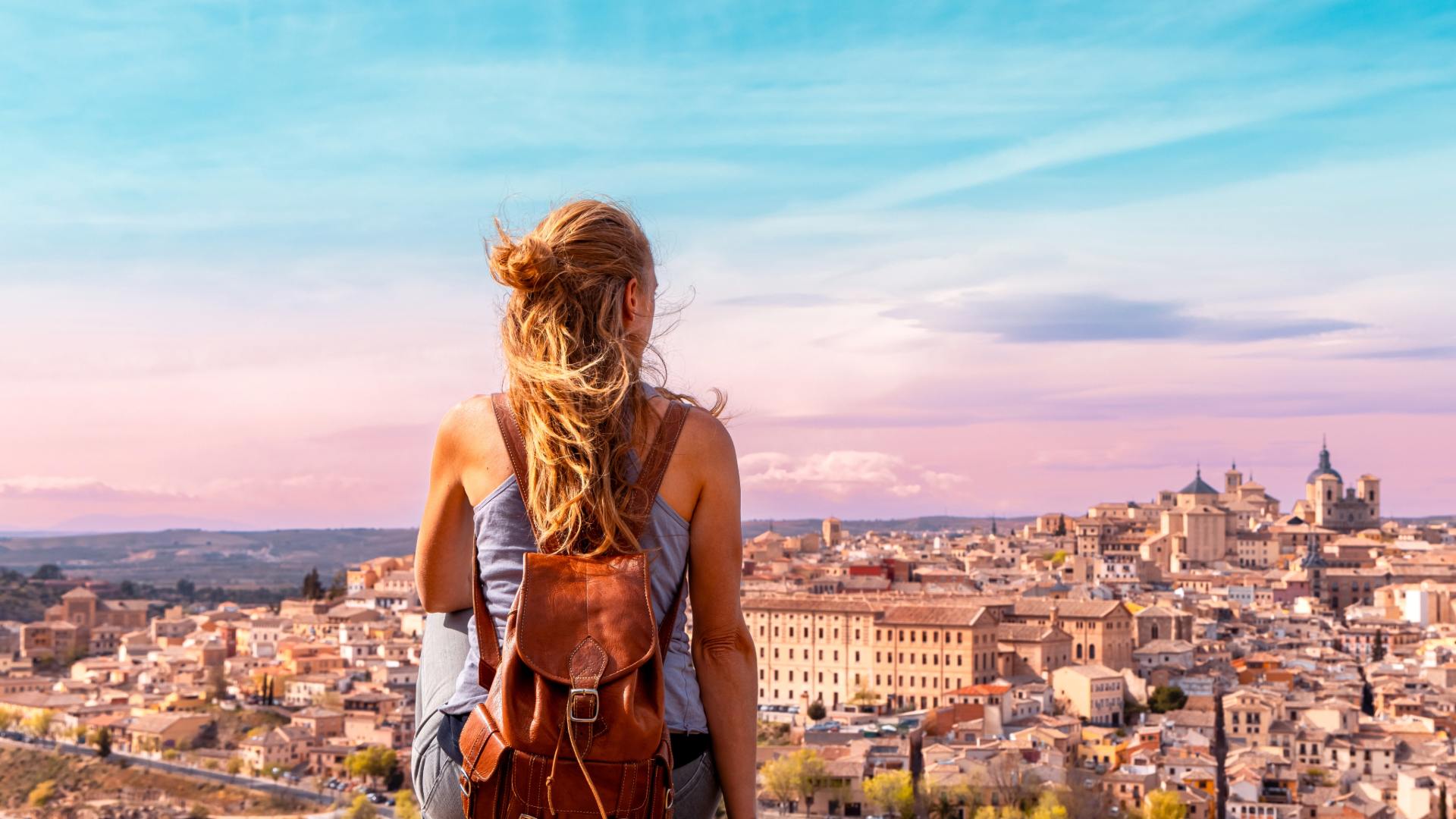Girl sat on hill overlooking a European city