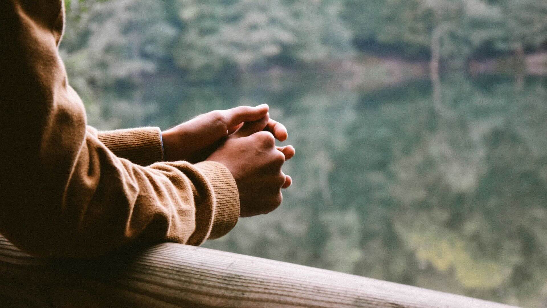 a photo of someones hand on a railing looking over some water.