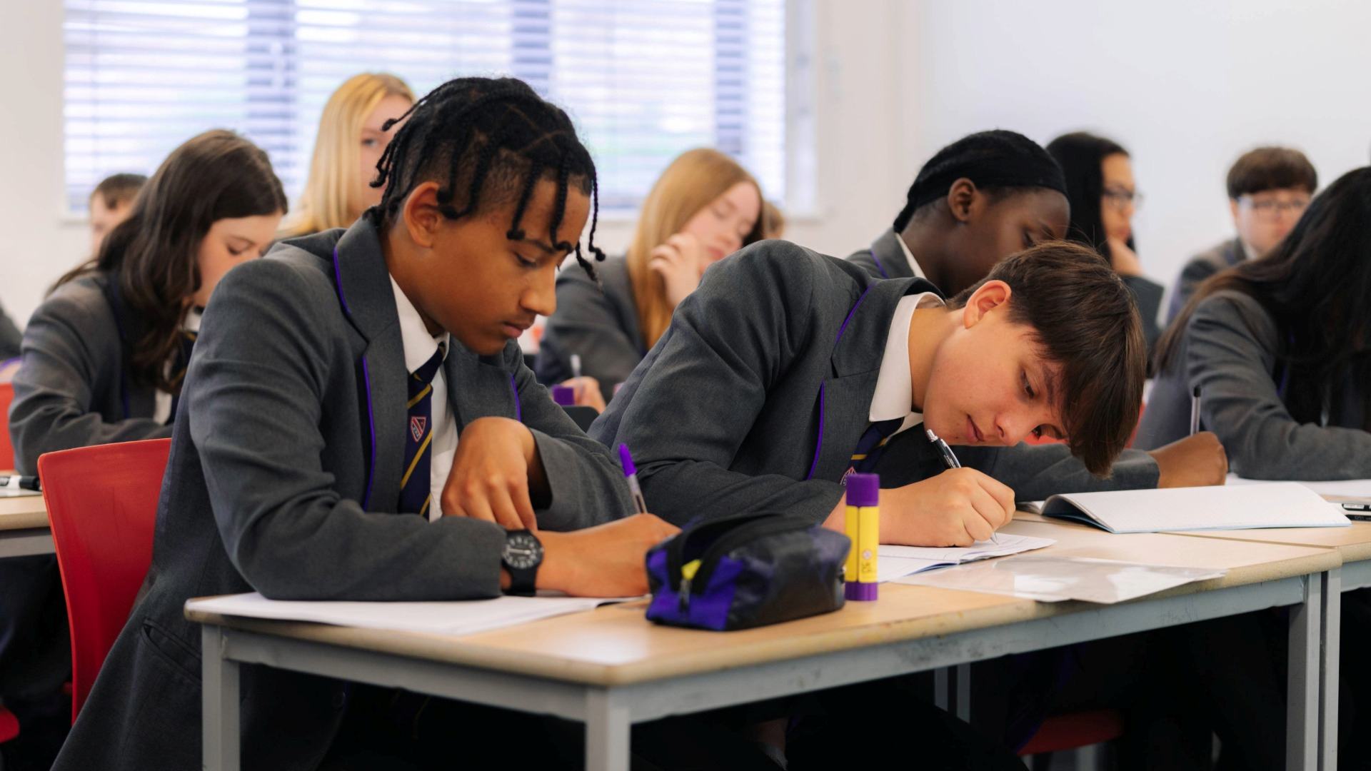 Secondary students sat at a table in class working.