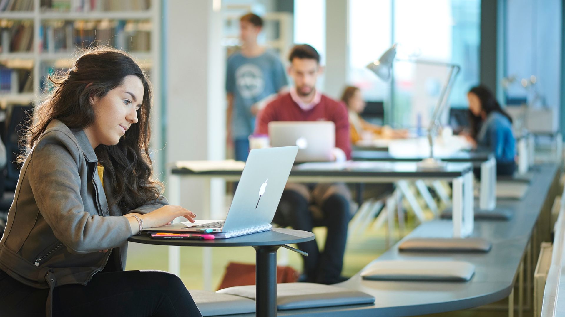 Student sat in a learning space, sat at a table with her laptop