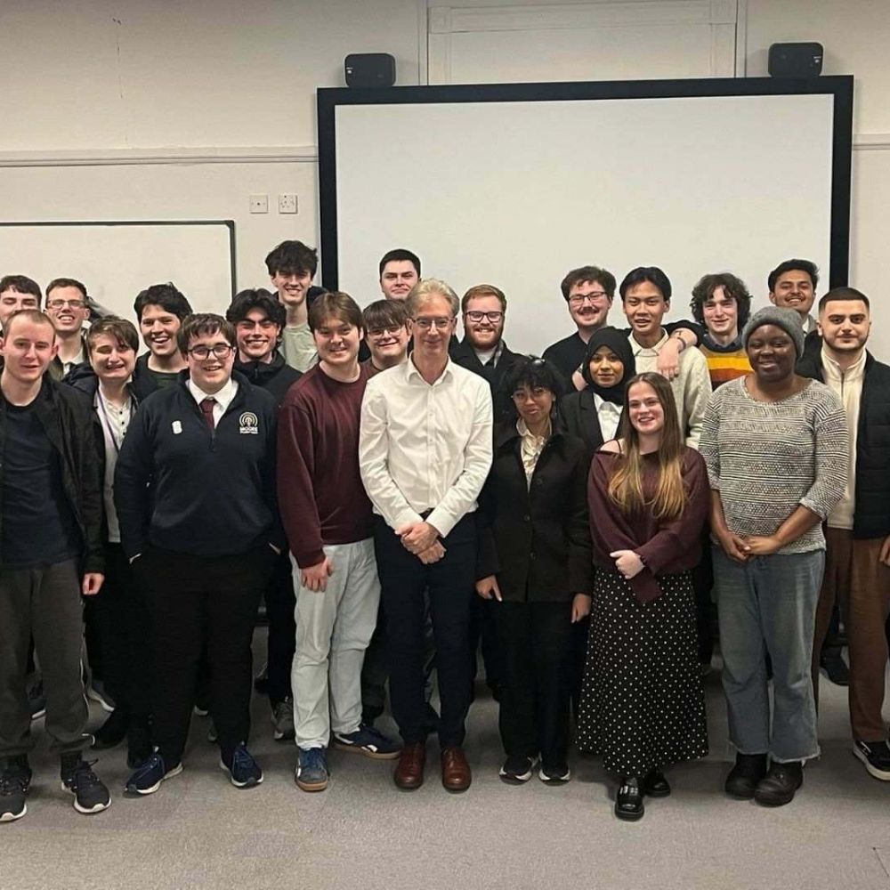 A group of students and staff gather together in a classroom