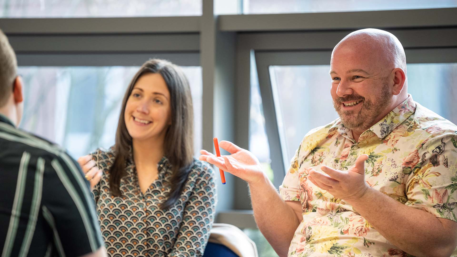 Three postgraduate business students having an enjoyable discussion in one of our classrooms