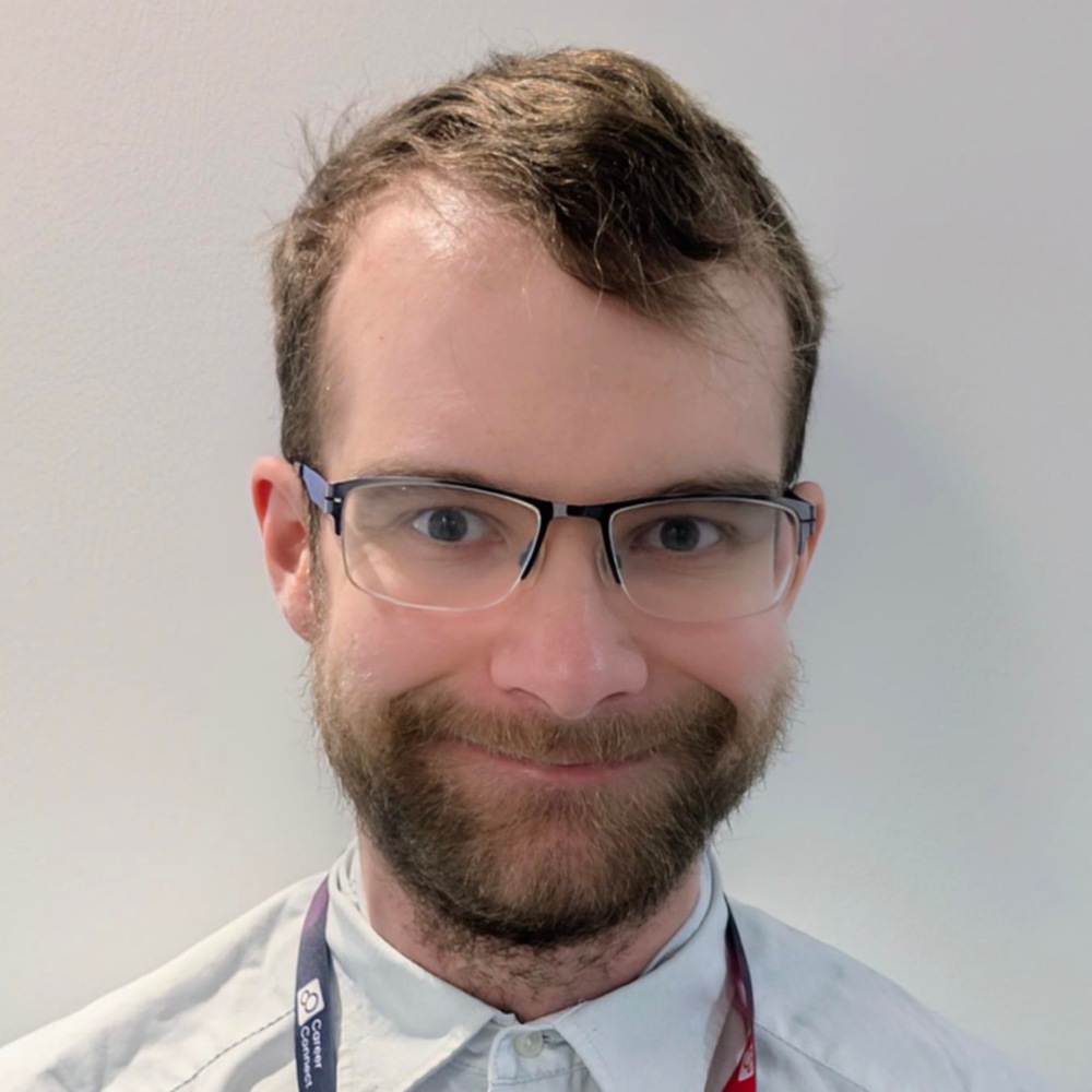 Simon wearing a light blue shirt, smiling directly at the camera. 