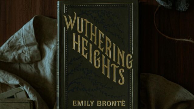 Wuthering Heights book in green placed on a table with cloth behind it.