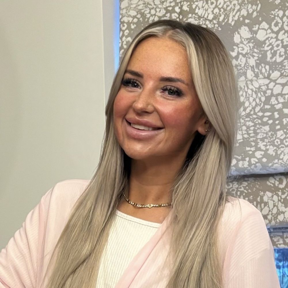 A young woman with blonde hair smiles at the camera.