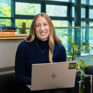 Grace Dunne working on her laptop, smiling at her friend